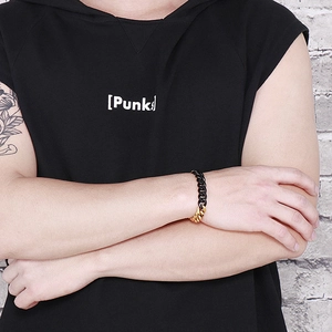 Men's punk black and gold dual-tone Cuban chain bracelet on tattooed wrist