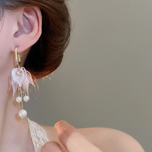 Detail of pink petal earrings with tassel chain and pearl drop on female model