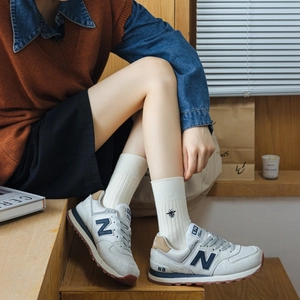Detailed close-up of bee embroidery on striped cotton socks paired with classic sneakers