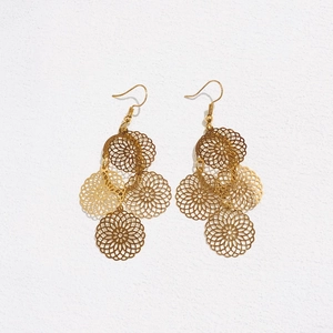 Macro detail of gold-toned bohemian earrings with hollow floral mandala discs design