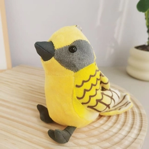 Cute yellow warbler plush bird keychain on a wooden tray with a minimalist background