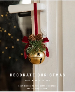 Macro view of Christmas red velvet bow with golden metal bell hanging on a white door