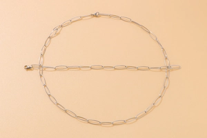 Detail of silver oval paperclip chain necklace and matching bracelet set in shiny steel
