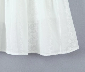 Dettaglio del tessuto di cotone bianco con ricami intricati e motivi in pizzo traforato