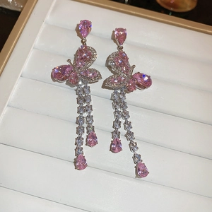 Gros plan sur les boucles d'oreilles papillon en zircon rose avec longues franges