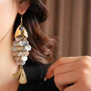 Detail of vintage fish-shaped earrings with shell scales and blue evil eye bead charm