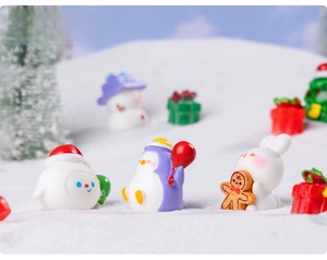 Vue détaillée de figurines de Noël miniatures en résine sur un fond de neige artificielle