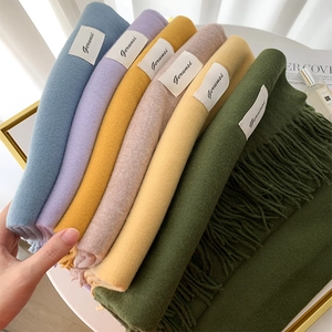 Detail showing various colors of cashmere scarves with fringe edges and brand labels
