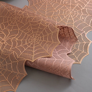 Close-up of laser-cut spider web table runner with bronze gold hollow pattern