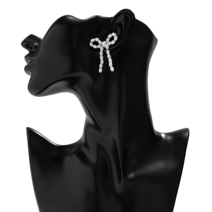 Detail of elegant pearl bow earrings featuring lustrous white beads on a mannequin