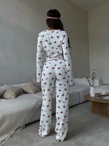 Detail view of white pajama set featuring red cherry print and delicate ruffled edges