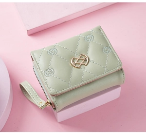 Close-up of mint green quilted leather wallet with floral embroidery and golden metal buckle