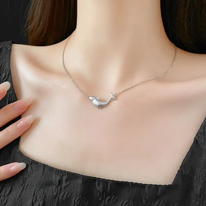 Close-up of a silver whale pendant necklace with zircons worn on a female model