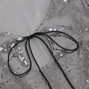Détail de sequins argentés et de laçage élastique noir sur une robe de soirée sexy