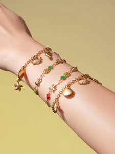 Gros plan de bracelets dorés avec breloques océaniques portés au poignet du mannequin