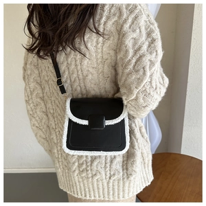 Détail d'un petit sac bandoulière rétro en cuir noir avec bordure en fausse fourrure blanche