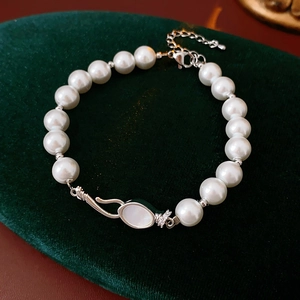 Detailed view of a pearl bracelet featuring a shell oval charm with zircon accents