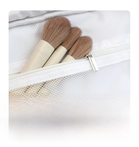Detail of white mesh makeup bag featuring flip-top design and internal brush storage