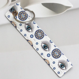 Detail of faux leather keychain featuring blue evil eye pattern with gold accents