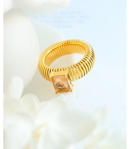 Macro detail of titanium steel ring with spiral texture and amber-colored glass stone