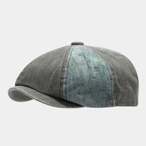 Macro detail of the stitched distressed denim panels and top button of the newsboy cap