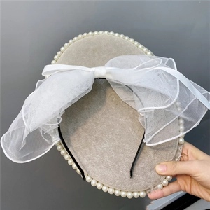 Detail of white mesh bow headband with faux pearl trim for bridal photography