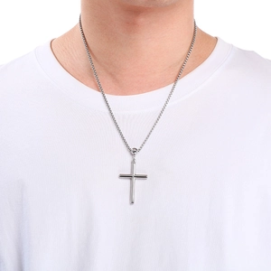 Close-up of polished stainless steel cross pendant with a box chain on a model