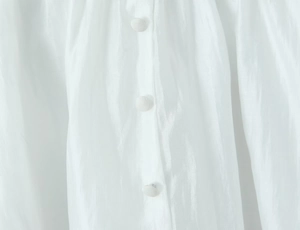 Detailed view of white translucent lace fabric with elegant matching fabric-covered buttons