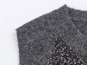 Close-up of grey mohair knit fabric with black sequins in geometric diamond patterns