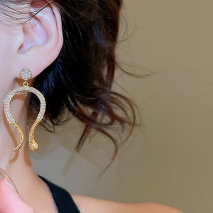Close-up of 14k gold plated snake earrings with zircon pavé setting on model's ear