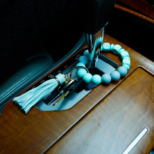 Detail of mint green silicone beaded LOVE bracelet keychain on a car dashboard