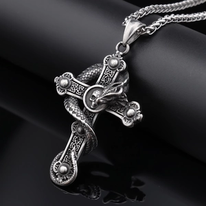 Macro shot of a detailed snake coiled around a silver cross pendant on a dark background