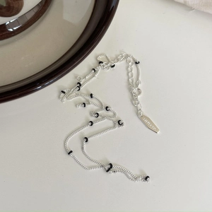 Minimalist 925 sterling silver beaded chain necklace with black beads on beige background