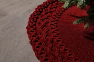 Close-up of red knitted Christmas tree skirt featuring intricate diamond textured patterns