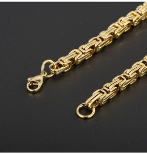 Macro view of 5mm gold Byzantine chain with lobster clasp on black matte surface