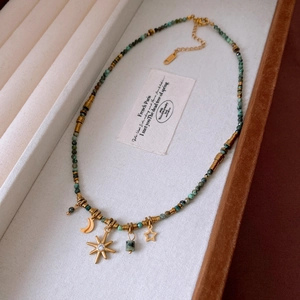 Detailed view of vintage beaded necklace with moon star pendants on velvet jewelry tray