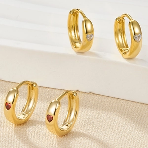 Detailed macro view of heart-shaped gold earrings with red and white sparkling zircon stones