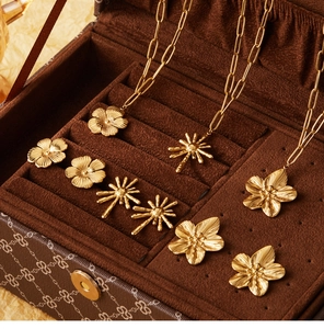 Close-up of gold flower pendant necklaces and stud earrings set in a velvet jewelry box