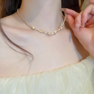 Detail of beaded necklace with shells and cream stones on model neck for fashion