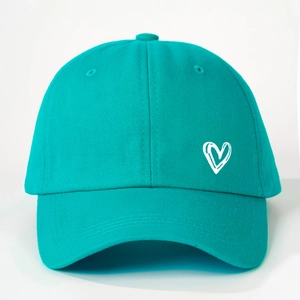 Detail of teal cotton baseball cap featuring a white embroidered hand-drawn heart design