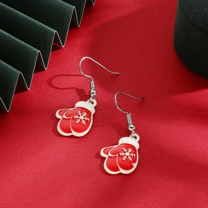 Close-up of red enamel Christmas glove earrings with white snowflake patterns