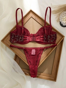 Détail d'un ensemble de lingerie en dentelle rouge avec broderie florale dorée