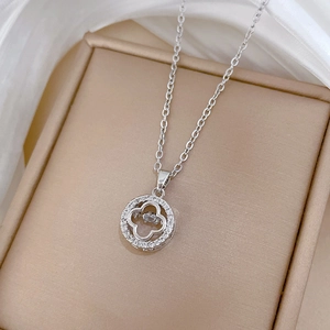 Close-up of sparkling silver clover necklace with zircon inlay on jewelry box