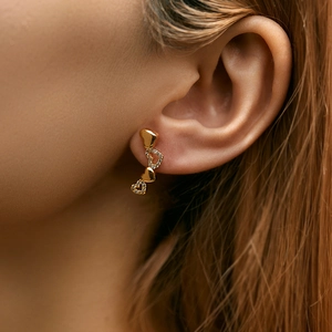 Detail of golden heart earrings with zircons shown on ear for a sweet and elegant look