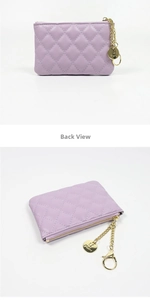 Detail view of purple quilted coin purse featuring gold chain and brand logo pendant