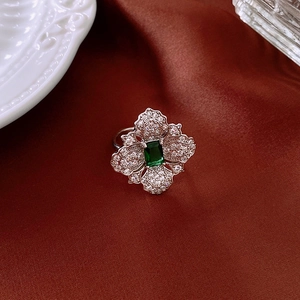 Detailed close-up of emerald green rectangle stone with crystal petals on red silk