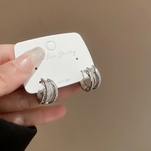 Macro detail of multi-layer crisscross silver hoop earrings with pave cubic zirconia stones