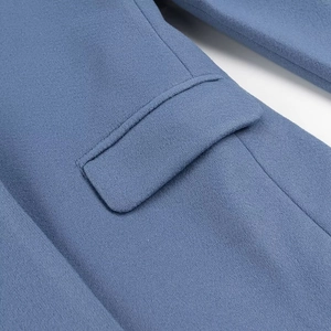 Detail of blue wool coat showing pocket flap texture and fine stitching craftsmanship