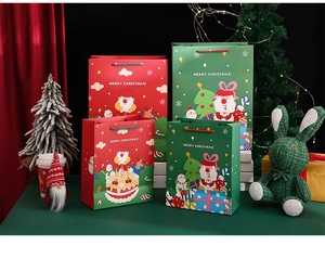 Detailed view of Christmas gift bags with cartoon patterns and woven handles on a green table