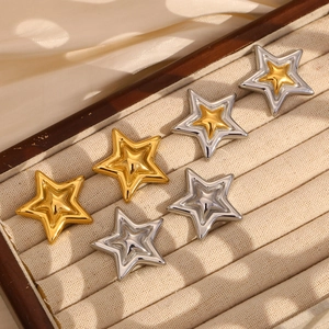 Detailed view of star-shaped 18K gold and silver plated earrings on velvet padding